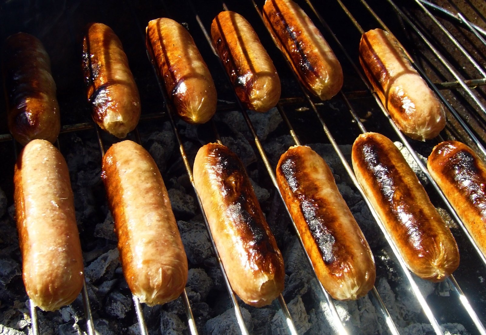  dogs being cooked on a grill outside