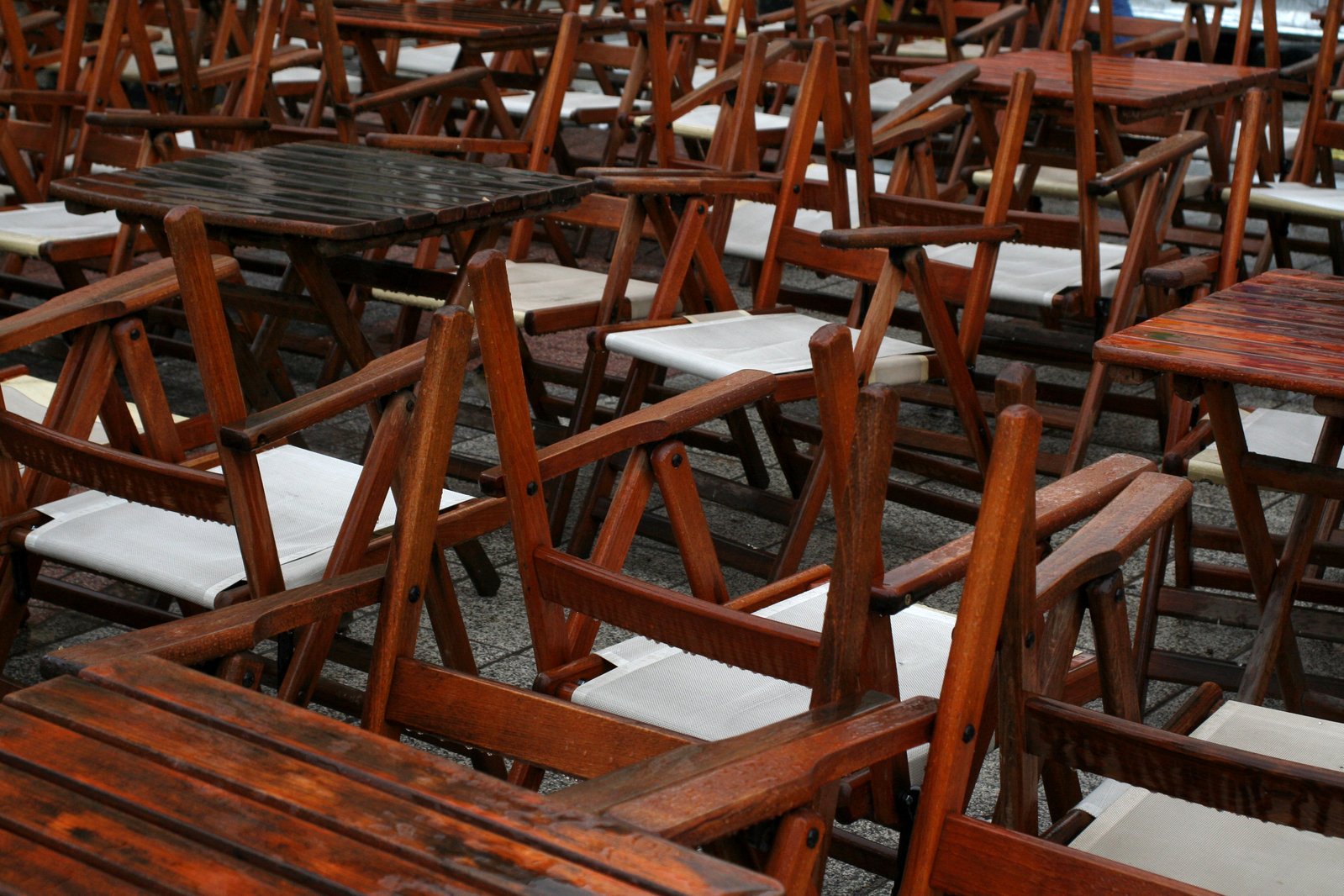many wooden chairs and tables lined up in a room
