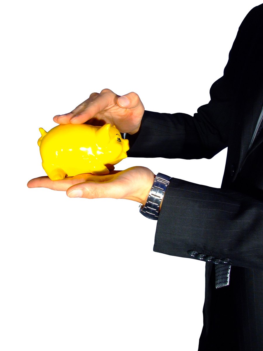 a hand holding a yellow plastic piggy bank