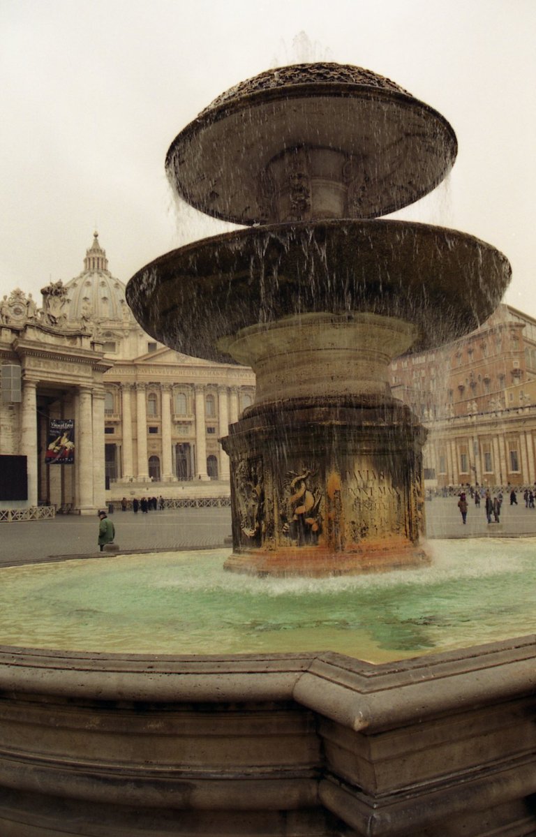 the fountain of the square with three tiers has water pouring down on it