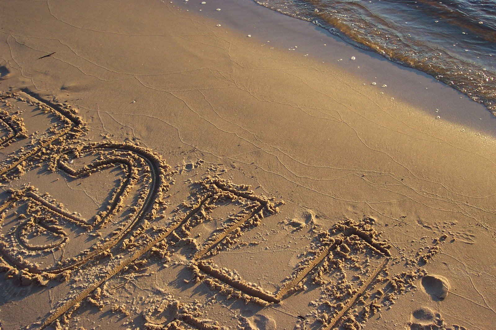 the words love is drawn in the sand on a beach