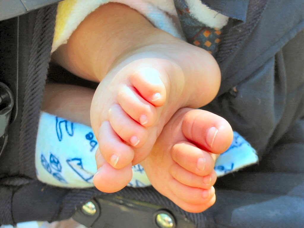 there is a small feet sitting in the stroller