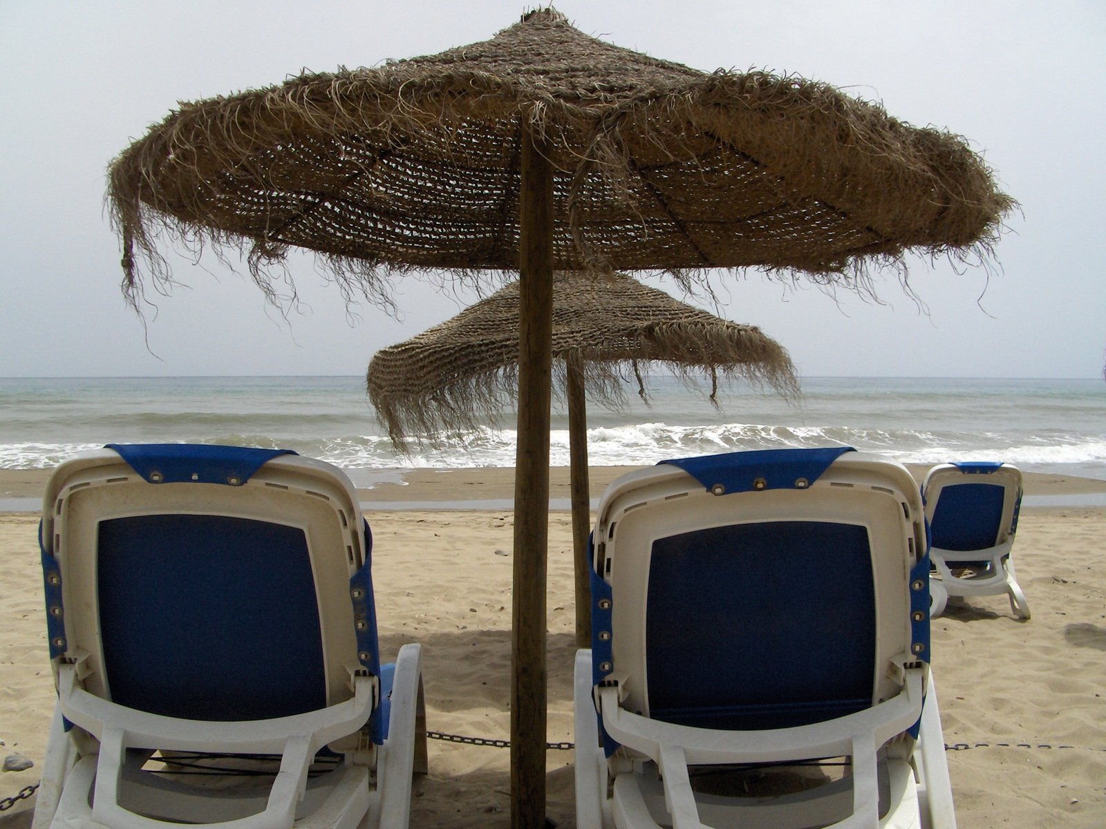 chairs and an umbrella in front of the ocean