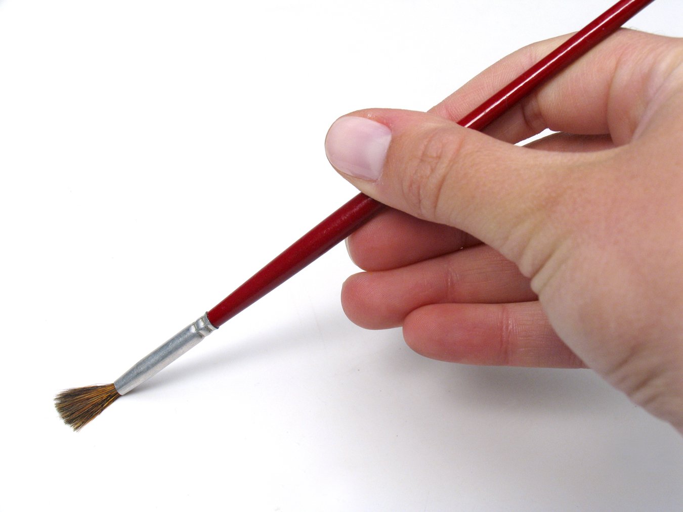 a person is holding a small red paintbrush