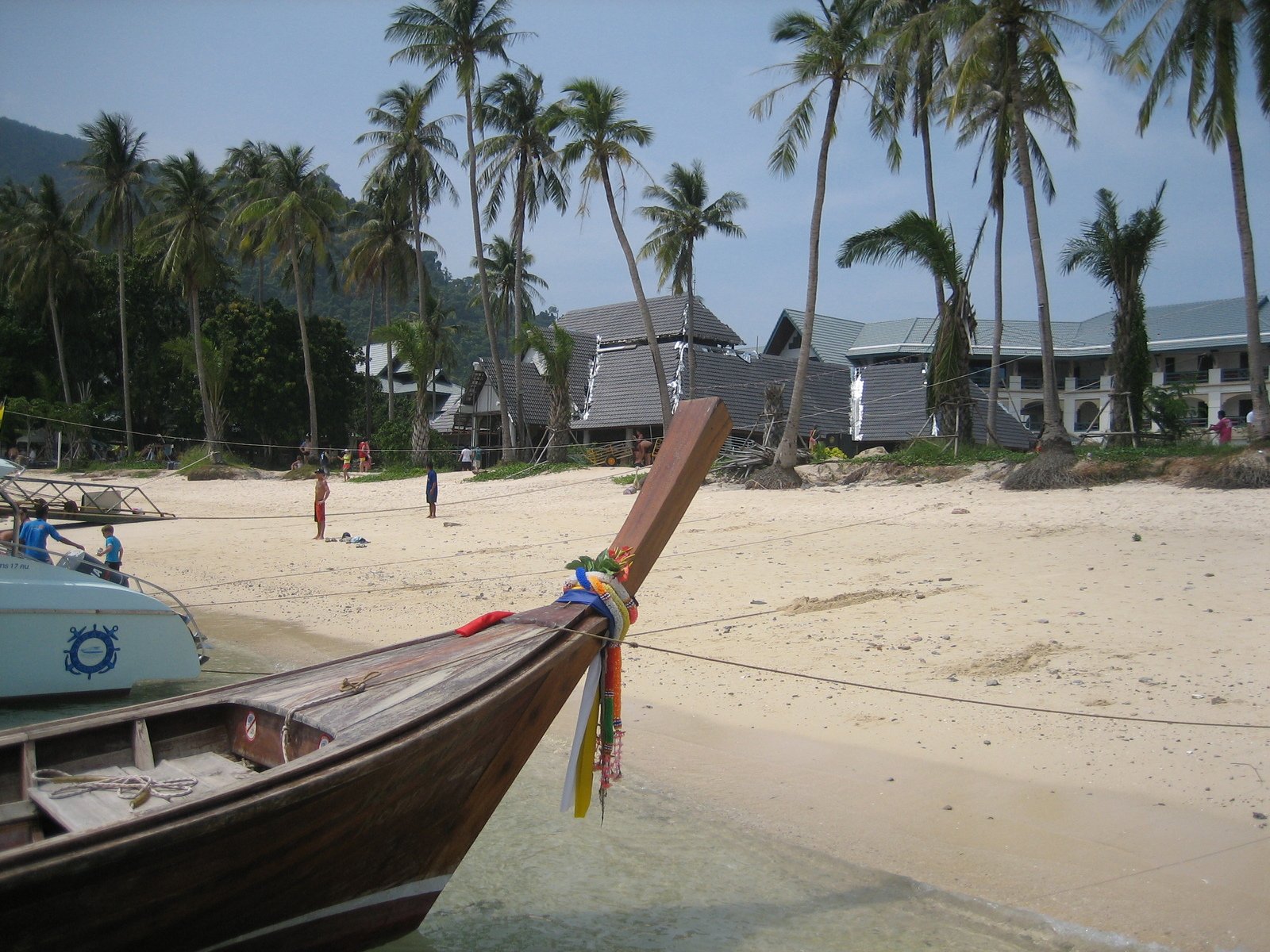 a boat parked on the beach near a white house