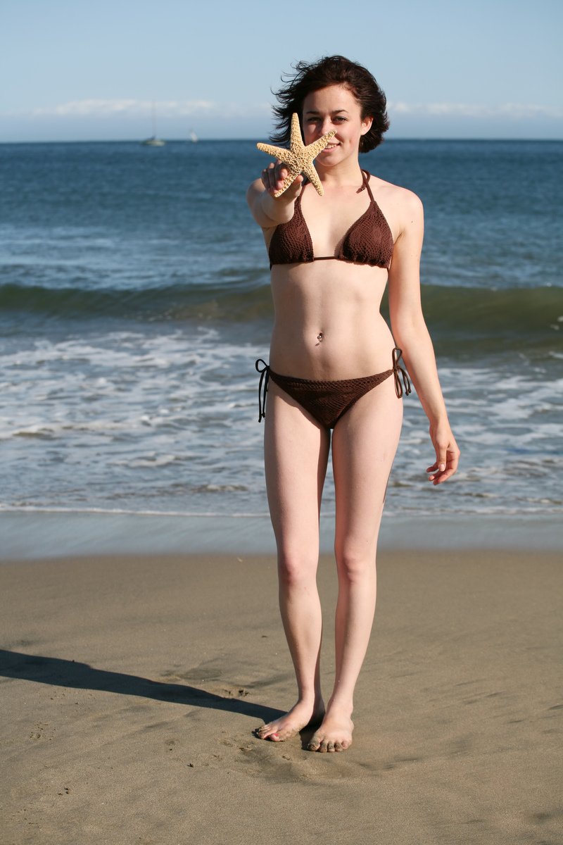 a woman with a starfish in her mouth on the beach