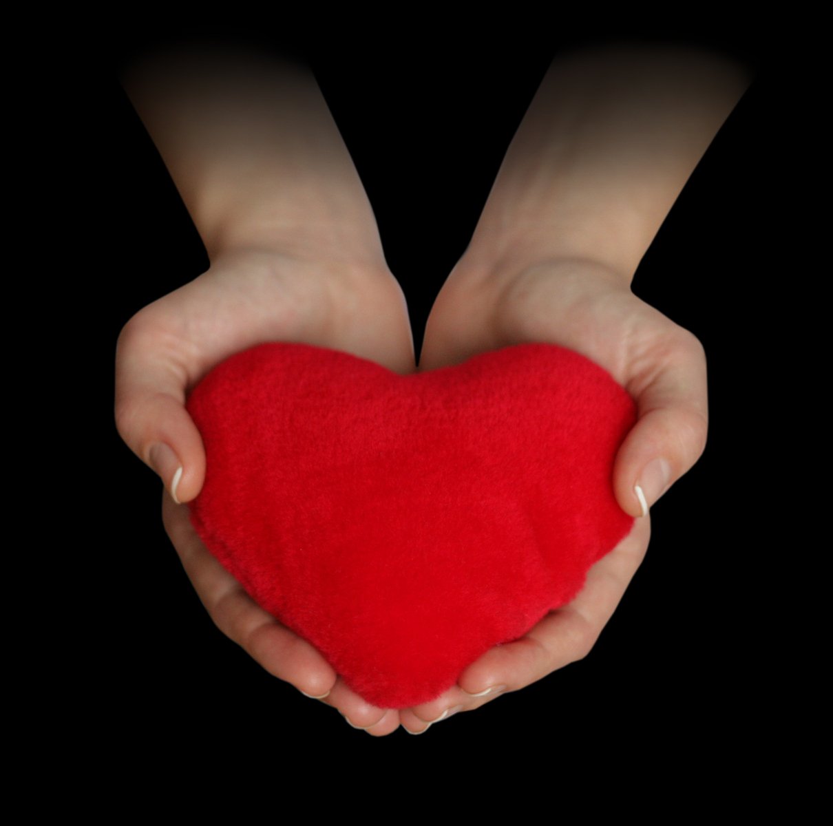 two hands holding a red heart while the other holds it