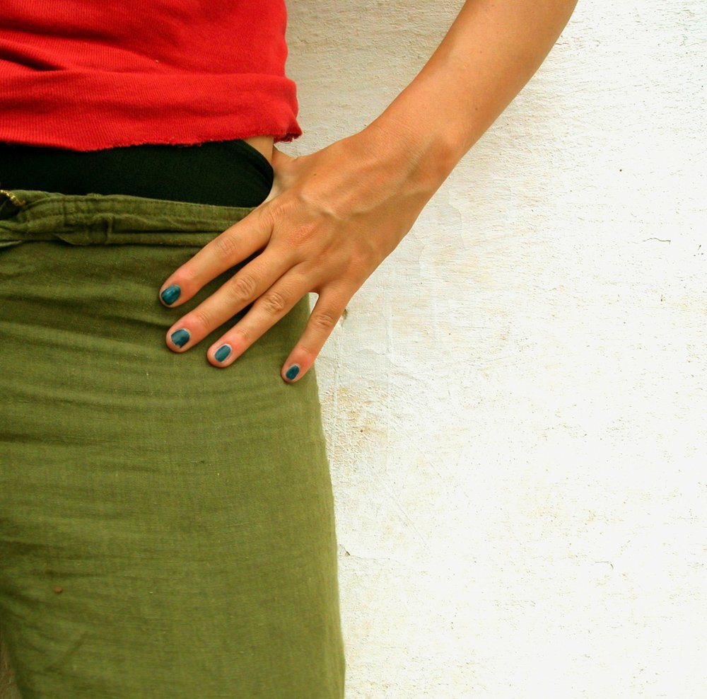 a woman's green skirted pants and red shirt has two fingers on the  of her left hand