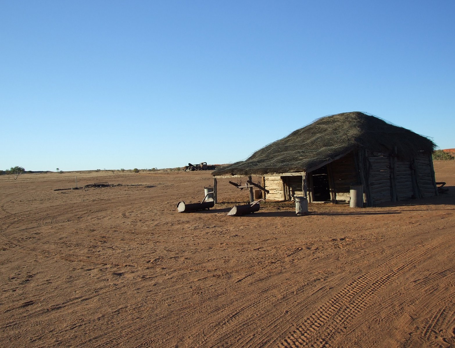 an out house in the middle of a dirt field