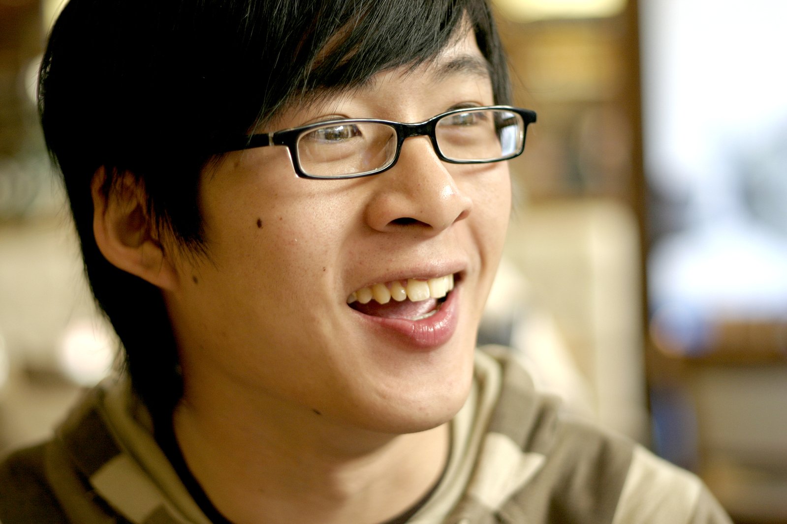 a young asian boy wearing black glasses, smiling at the camera