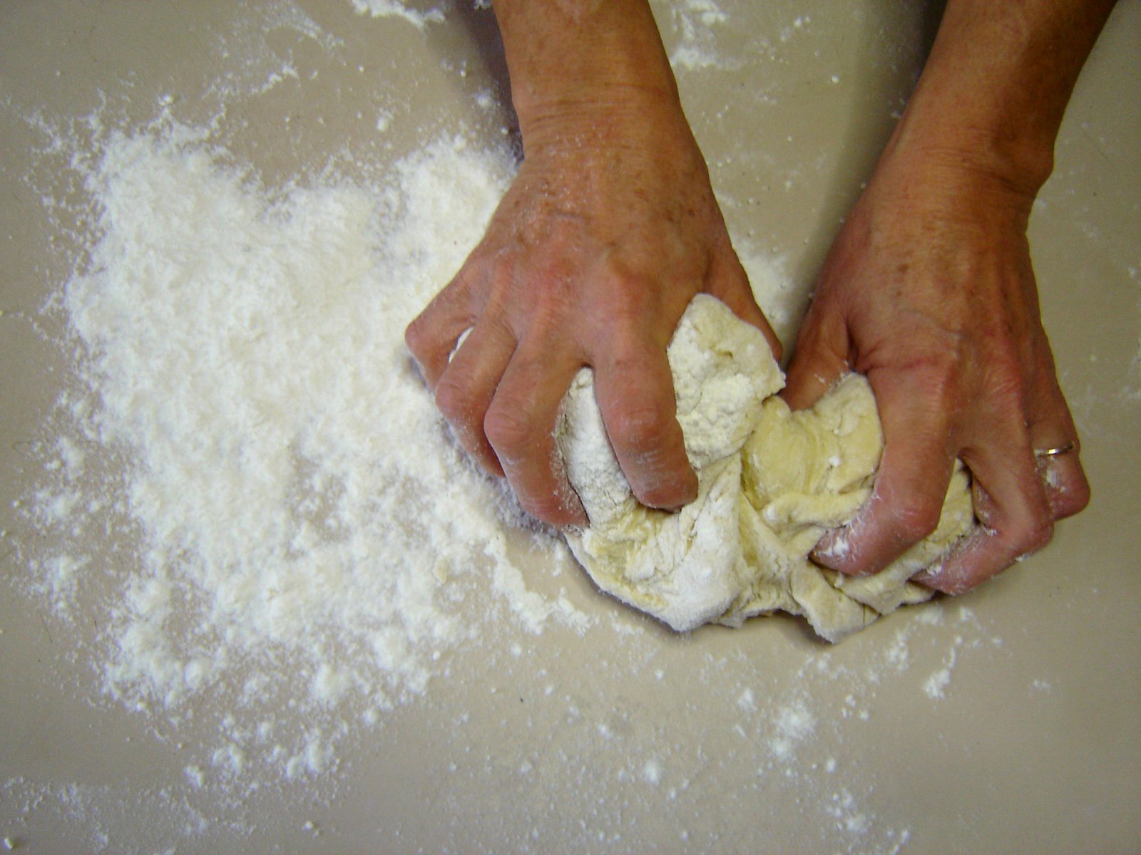 someone kneading out food on a flour counter