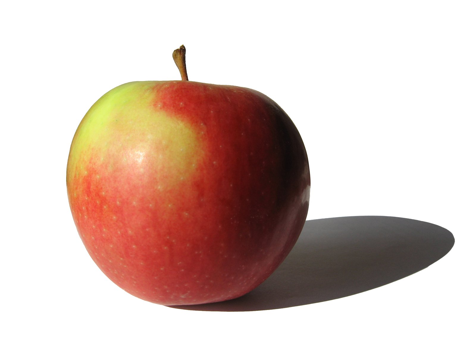 a red apple is sitting on a white surface