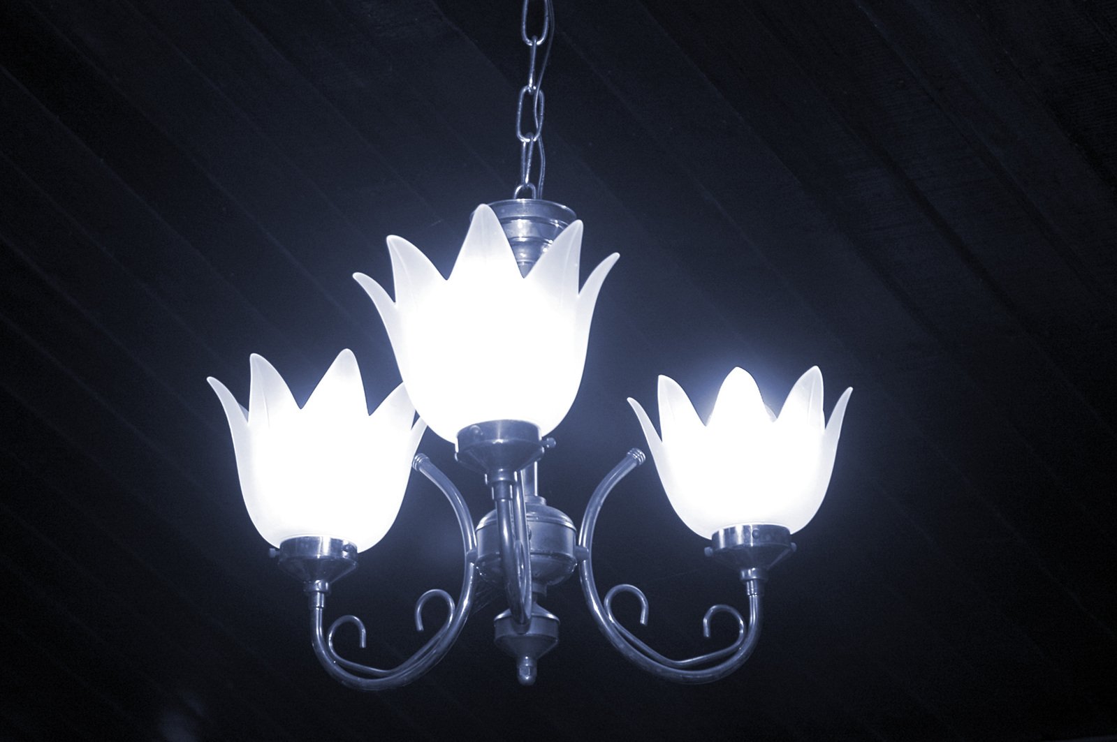a chandelier with four white lights in a dark room
