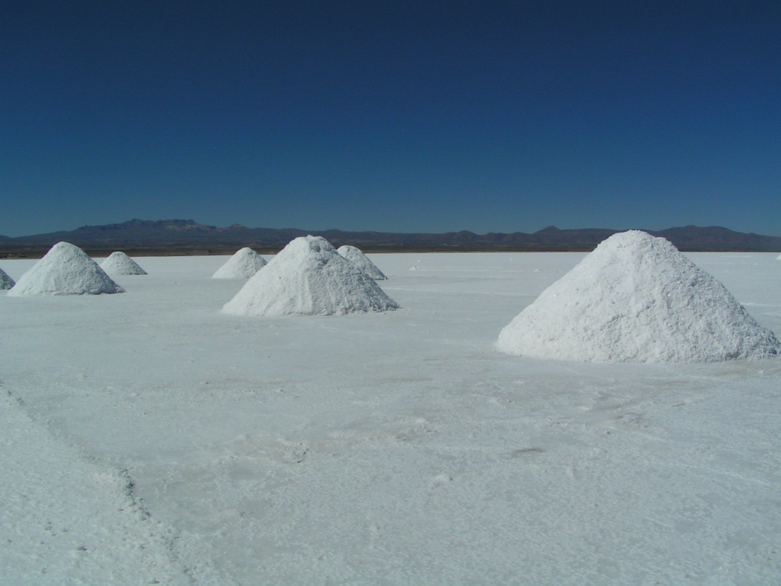piles of white sand sit in the middle of a desert landscape