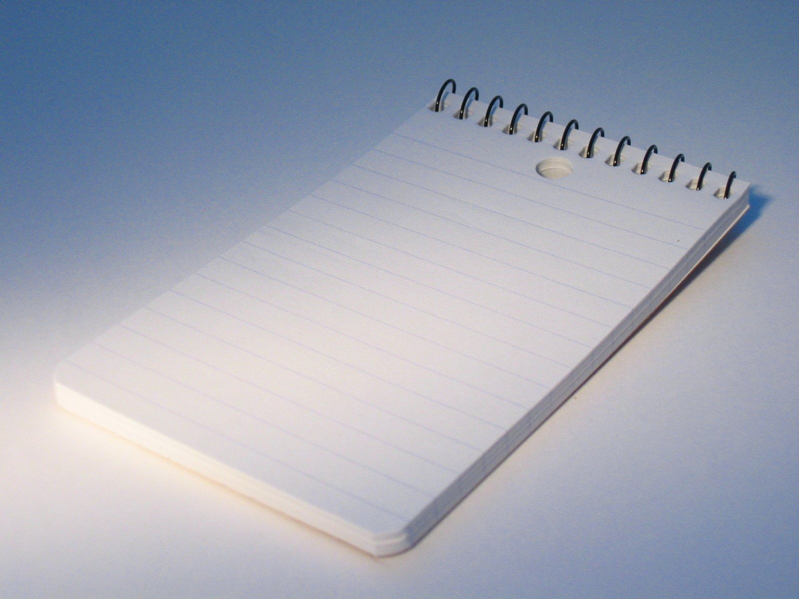 an open blank notebook with pencils and lined pages