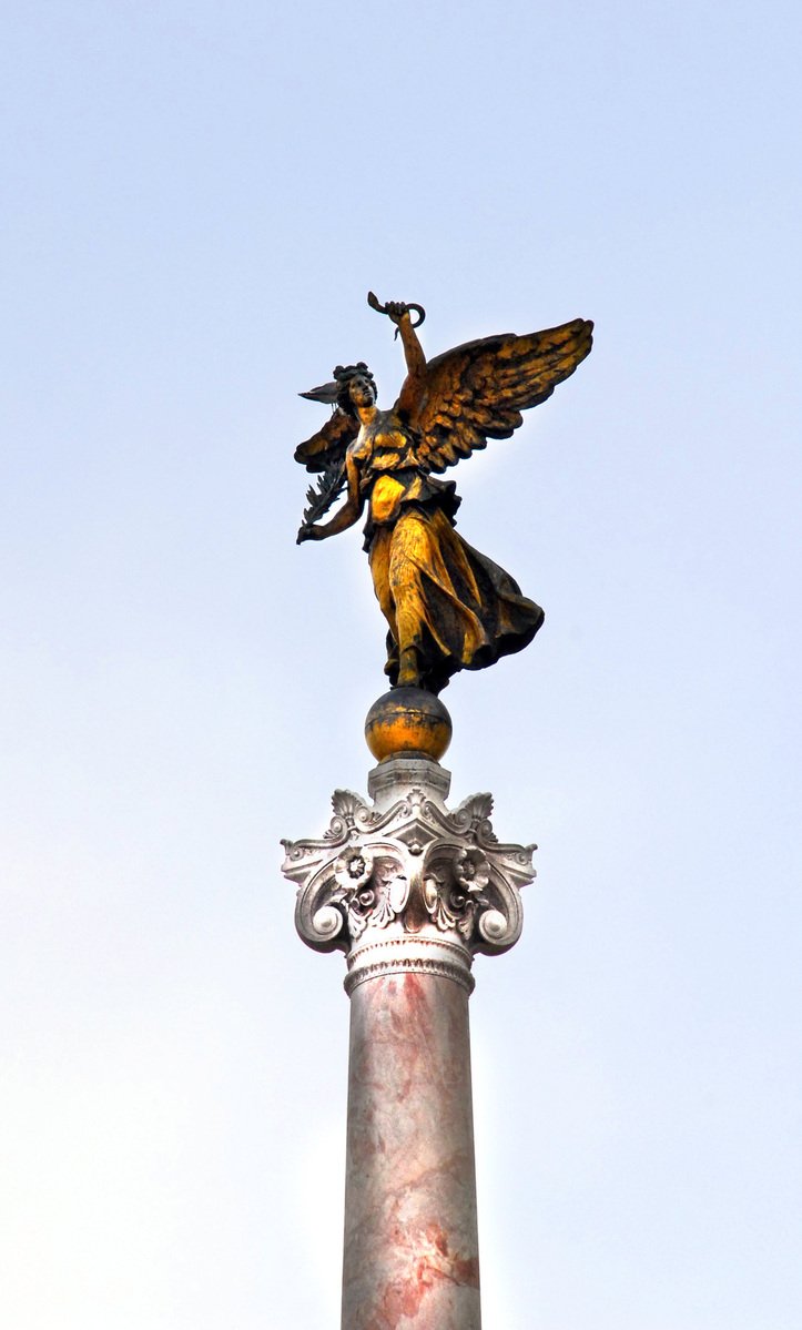 a statue is pictured on top of a tall pillar