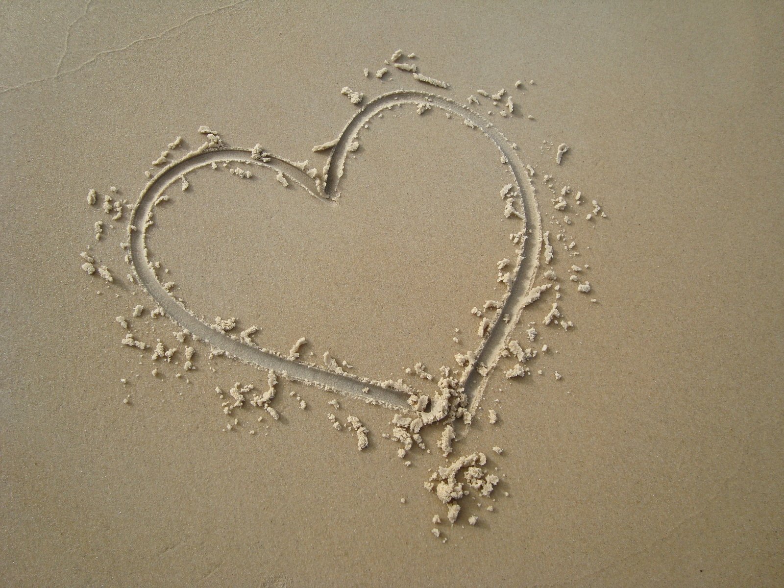 a heart drawn in the sand with birds at the beach