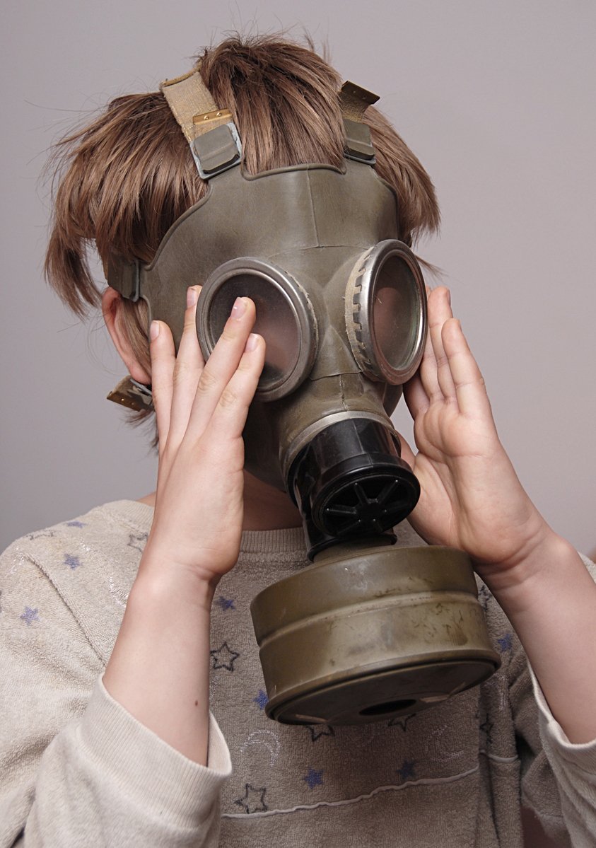 a woman in a gas mask covering her face with both hands