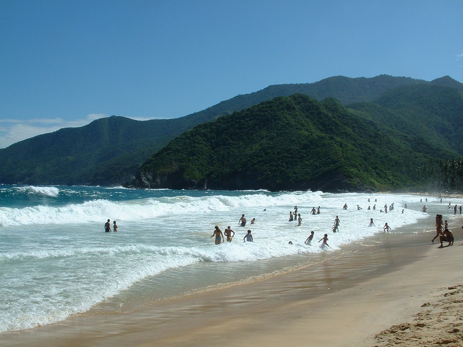 many people on the beach with a mountain in the background