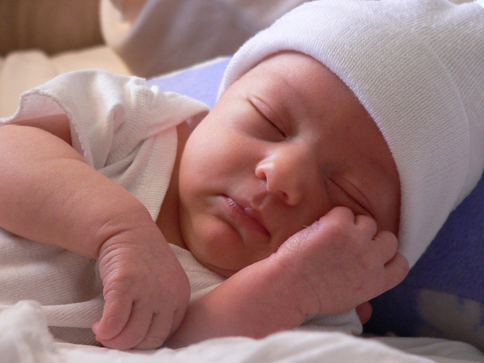 a small baby wearing a white cap laying down