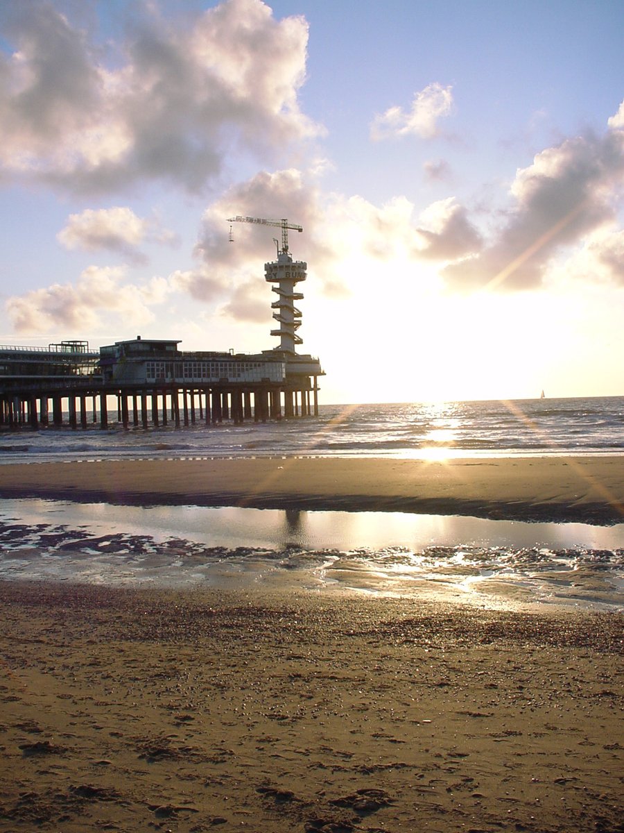 a pier on the beach near water and sun