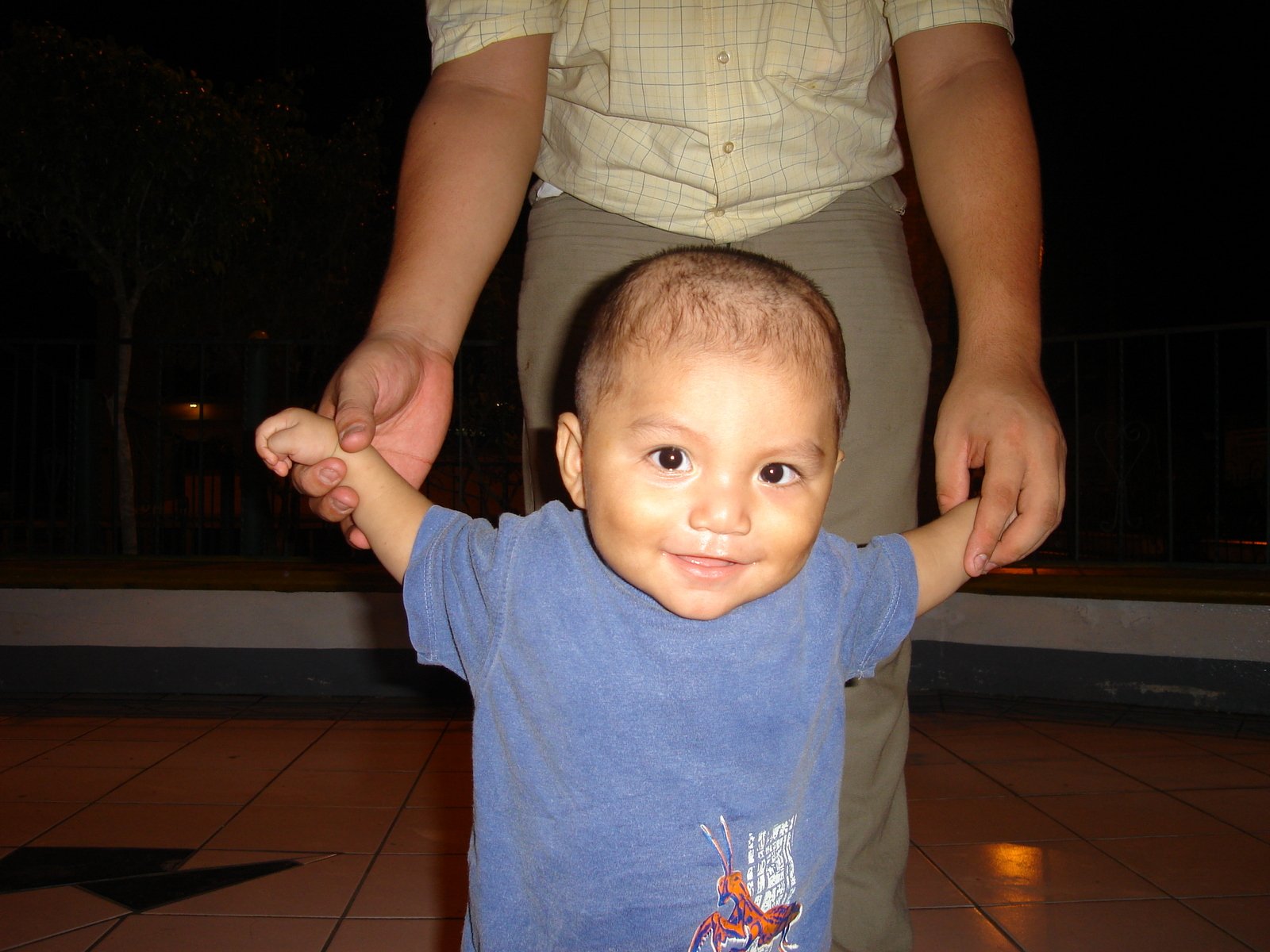 a toddler standing up and holding the arm of an adult