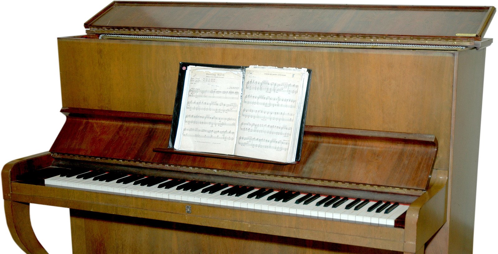 the upright wooden upright piano has sheet music in it