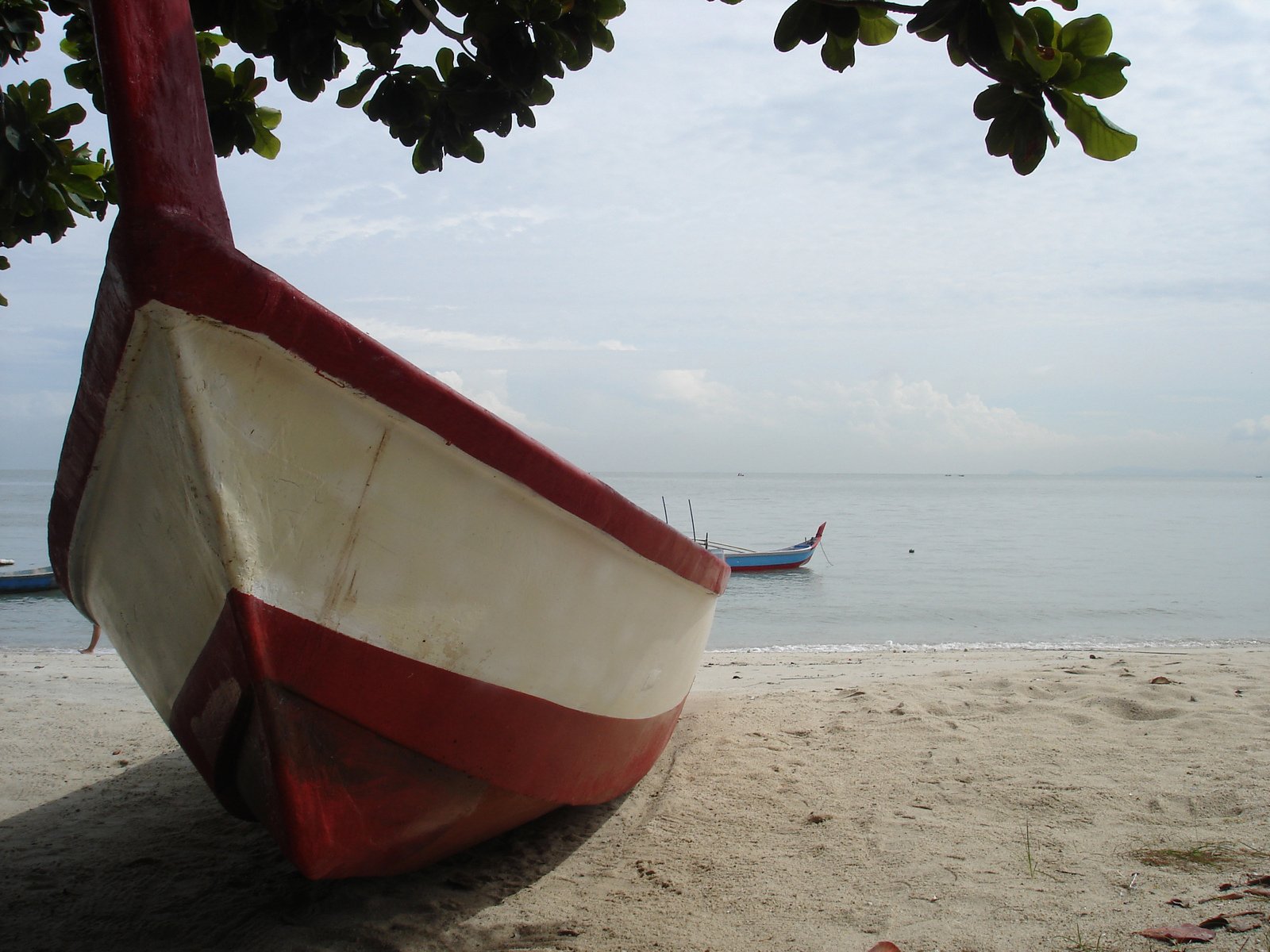 a boat sitting on top of a beach covered in sand