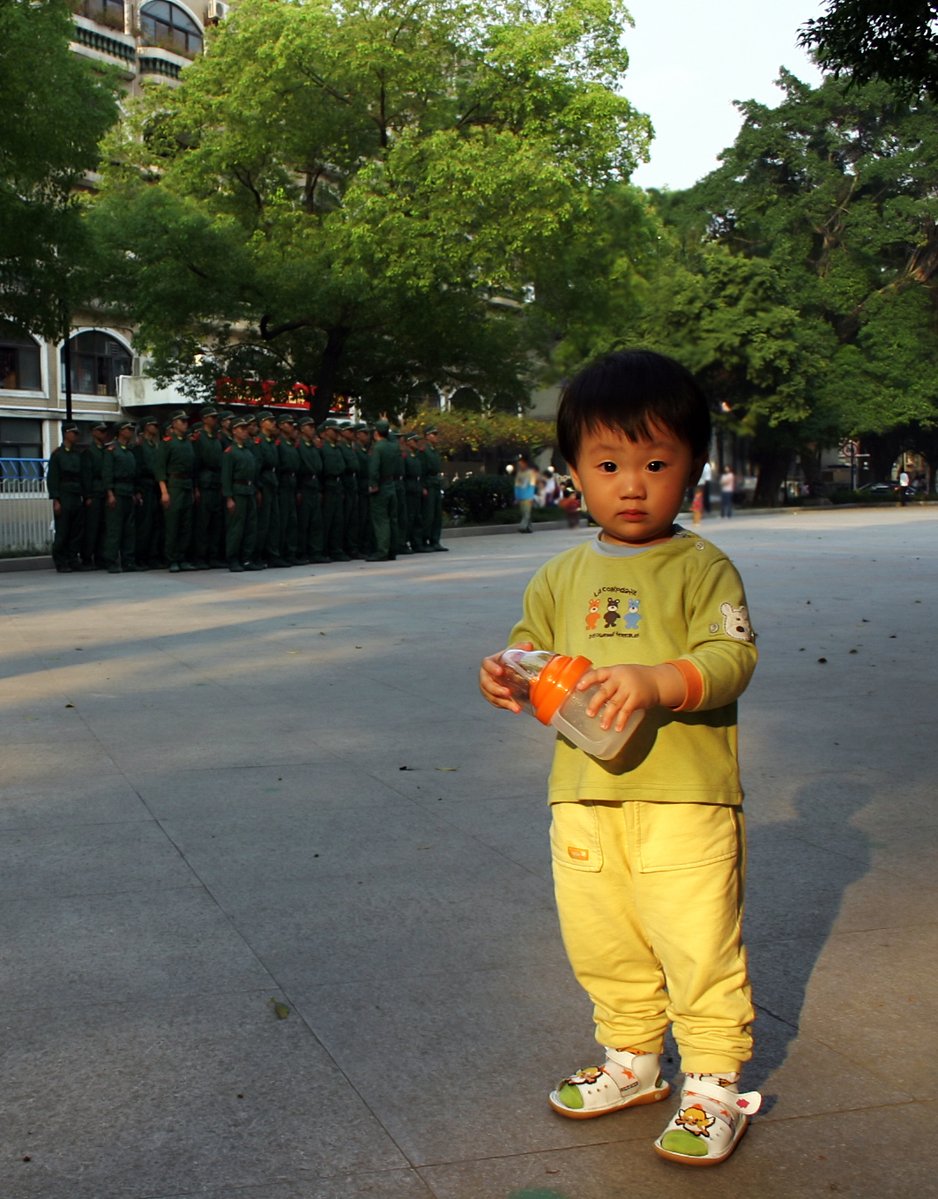 a little boy in yellow holding an orange object
