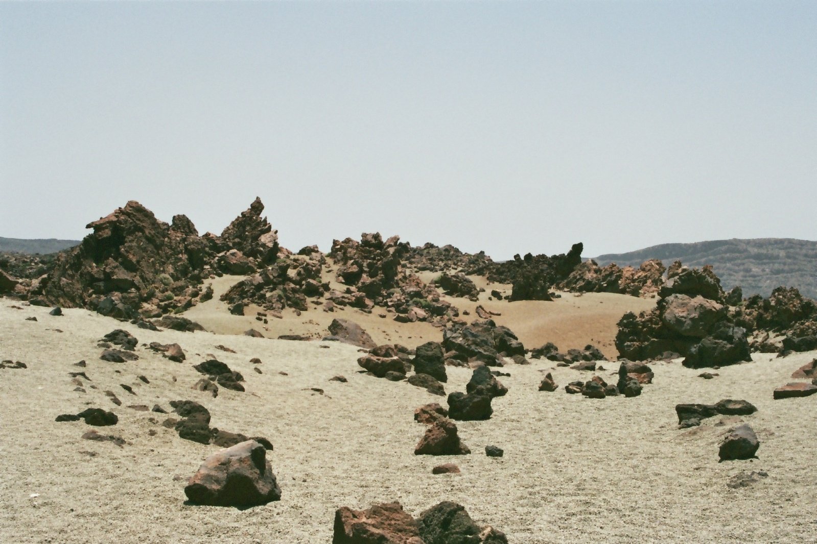 a dirt and rock filled plain under a blue sky