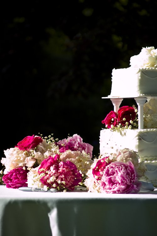 a tall three tier cake on a table with flowers