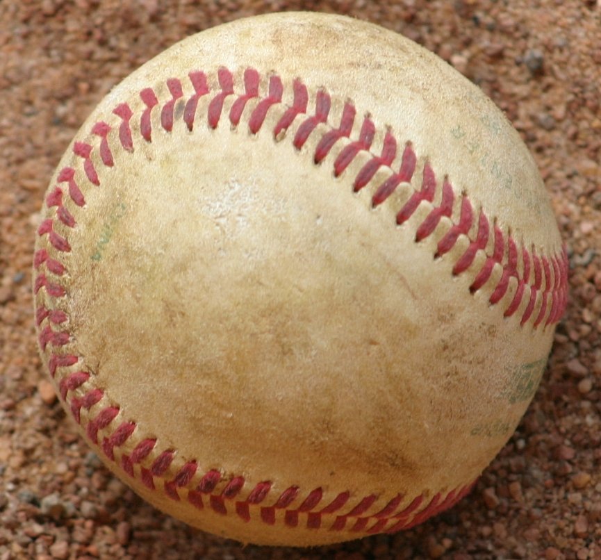 an old baseball in the dirt and sand