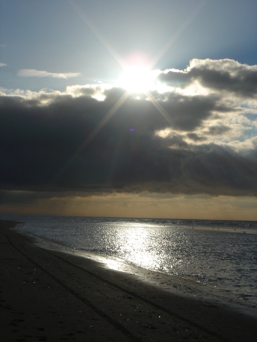 sun shining through a cloudy sky over the ocean