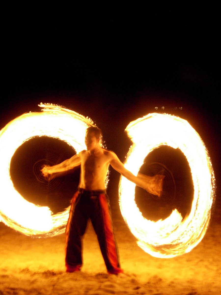 the man is juggling fire while posing