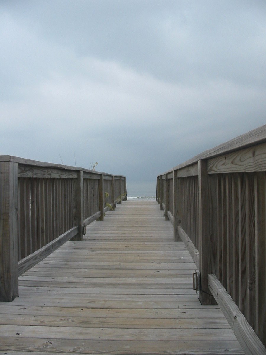 wooden walkway over looking beach with railing around