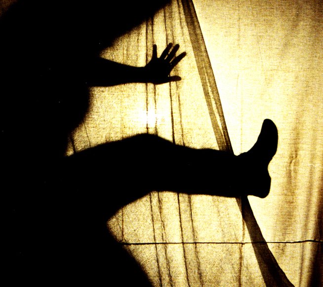 a silhouette of someone standing by a curtain