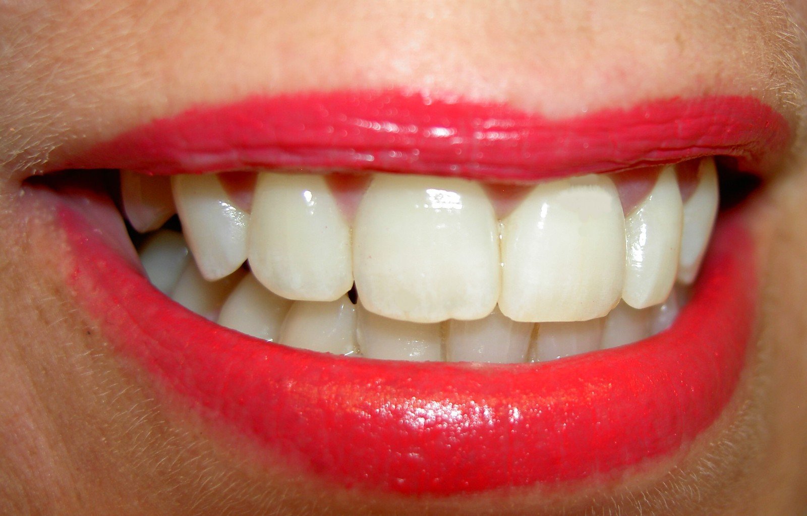 a close up of a person's mouth, with bright red lipstick on the lips