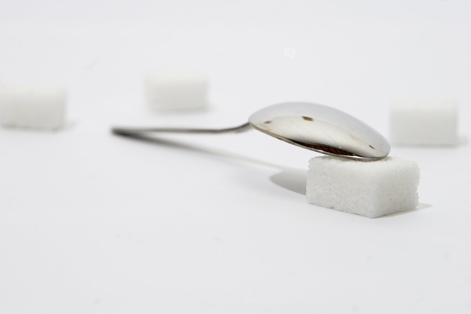 some spoons and cubes of sugar sitting on a white table