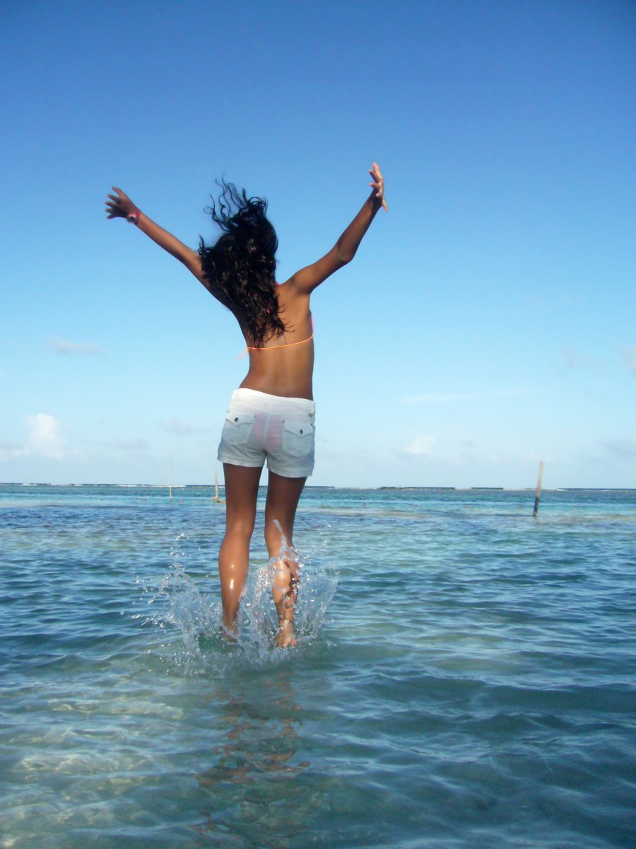 woman in swimsuit jumping off water into ocean