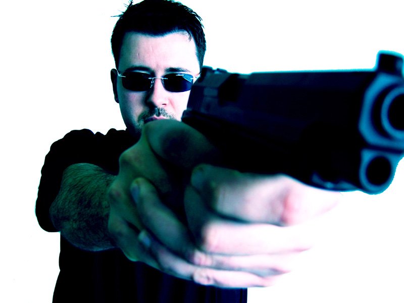 a man wearing sunglasses holding a gun up to the camera