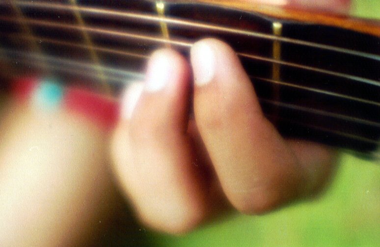 person playing guitar with blurry po of hand