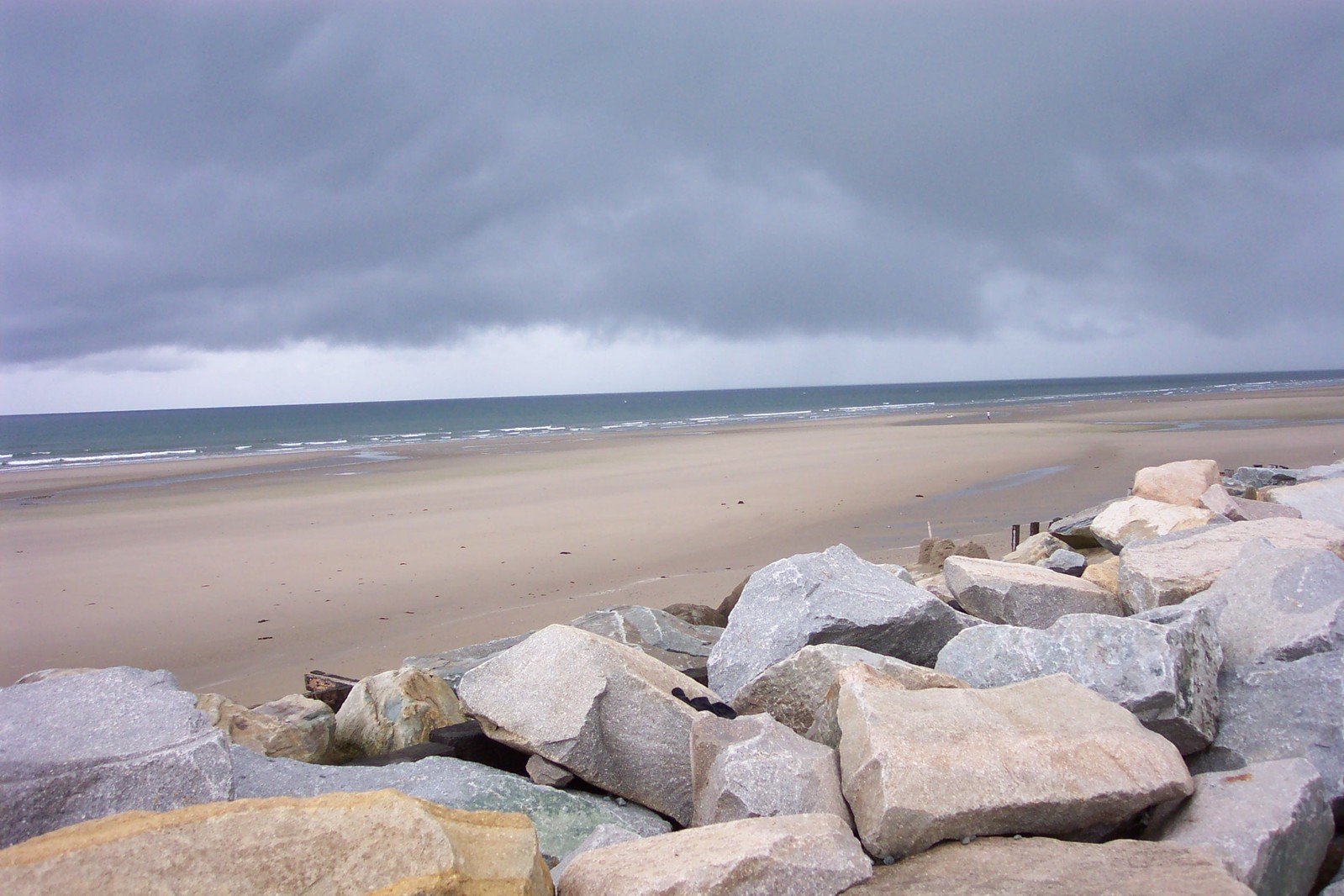 large rocks and boulders stand on the beach near the water