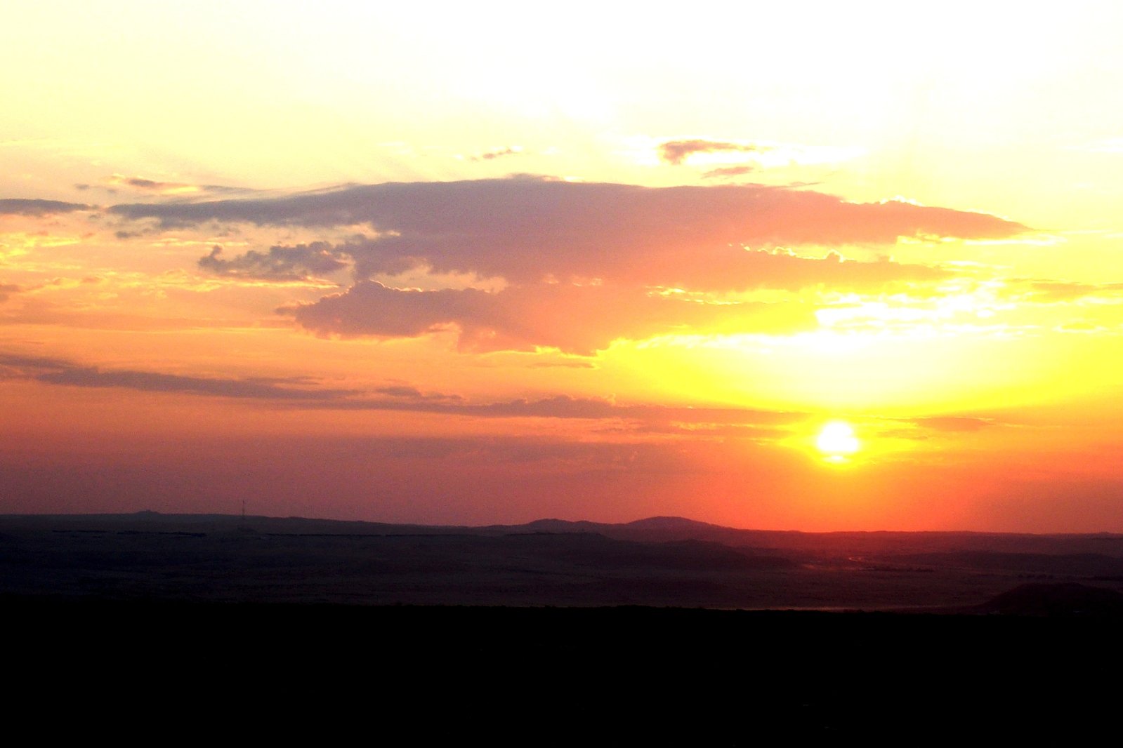 the sun is setting over a valley with hills in the distance