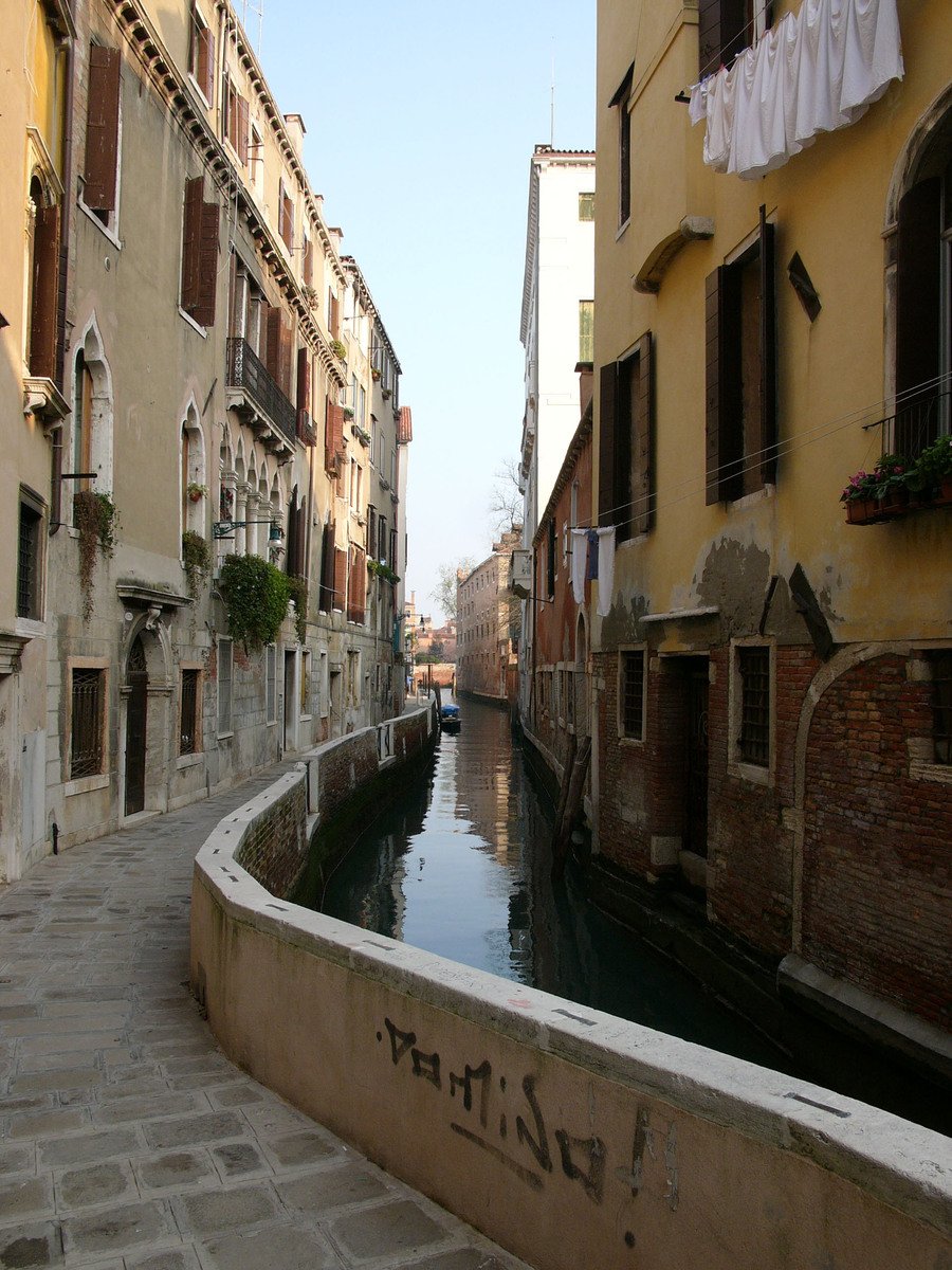 a canal between buildings with laundry hanging on a line