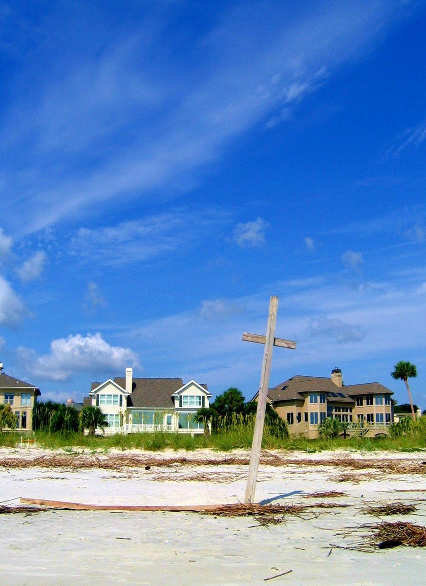 an airplane flying over a sandy beach on a sunny day