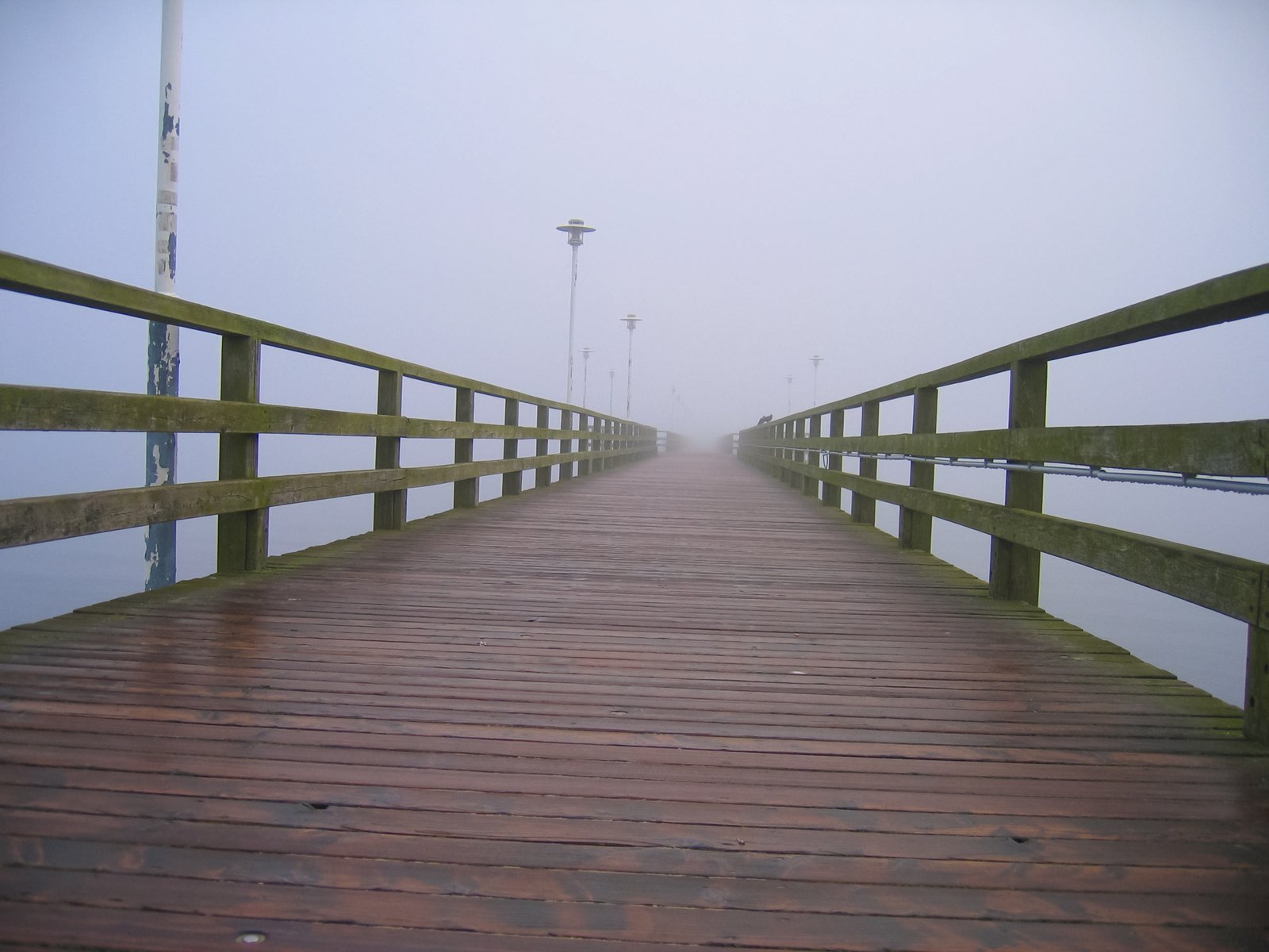 the wooden dock is surrounded by fog as it floats in the water