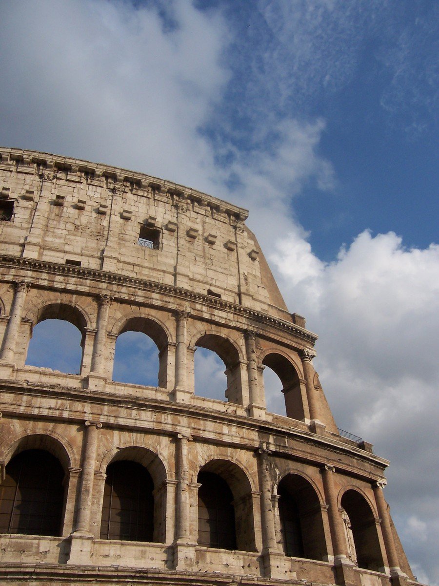 an ancient structure with arched window openings in a cloudy sky