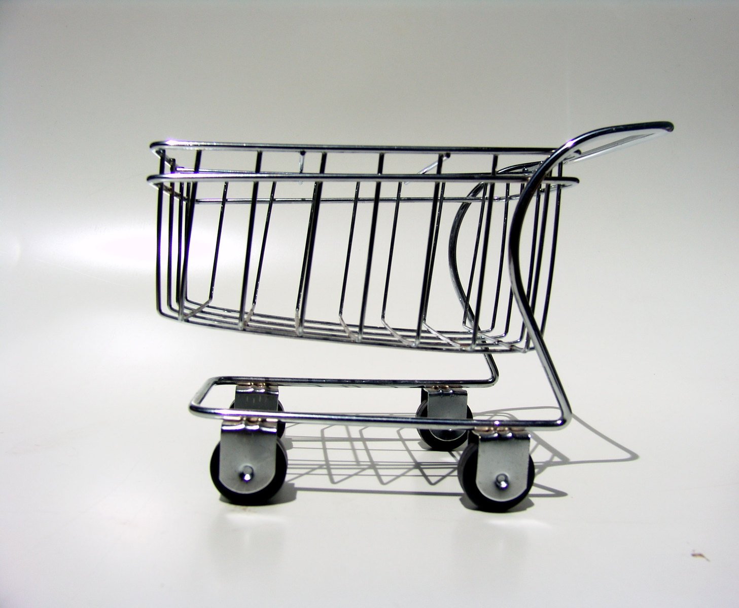 a silver metal shopping cart sitting on top of a white table