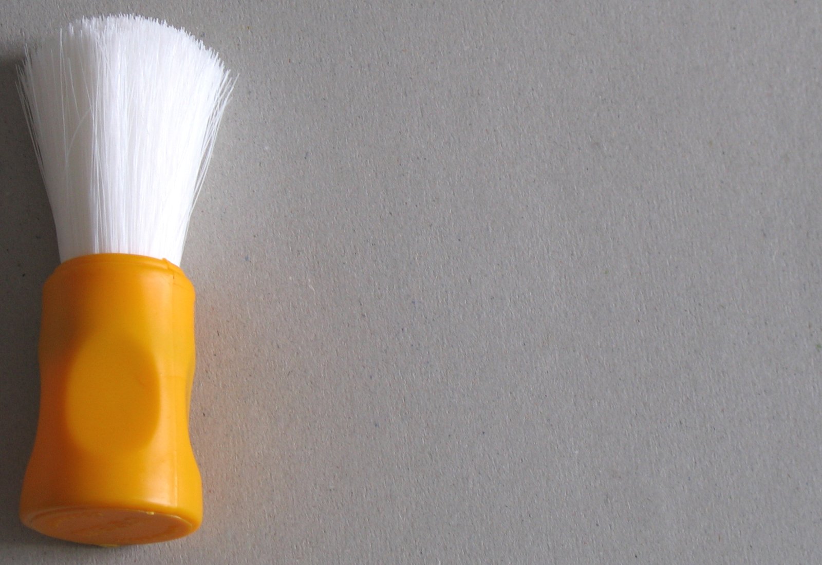 a white and yellow shaving brush on a wall