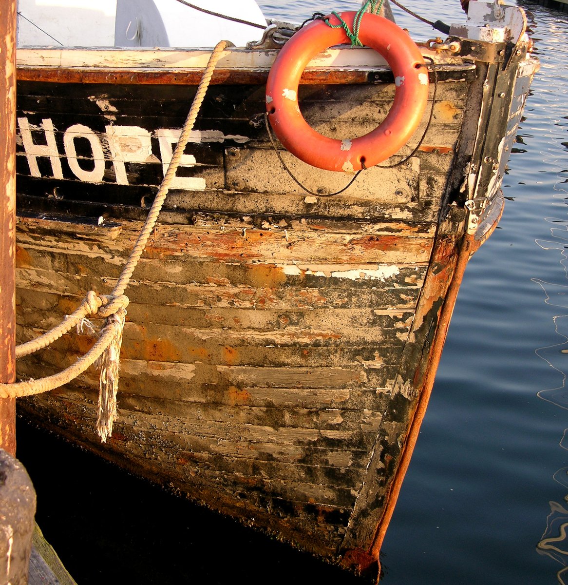 a brown and white boat with an orange life ring tied to it